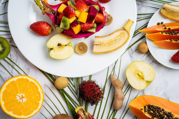 Exotic fruits and tropical leaves on table
