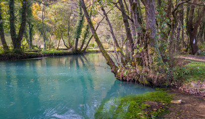 Turquoise color of water in the autumn on the river Janj surrounded by forest.