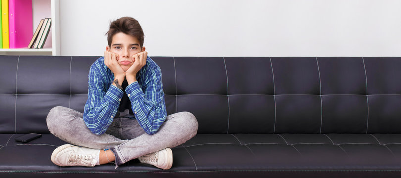 young teenager boy on sofa with bored expression