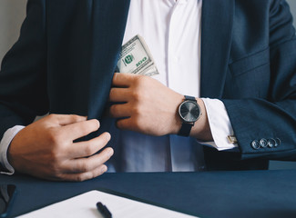 Businessman putting banknotes of dollars  in suit pocket. Corruption concept