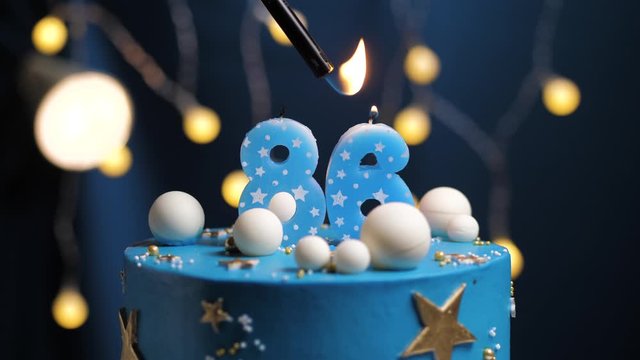 Birthday cake number 86 stars sky and moon concept, blue candle is fire by lighter and then blows out. Copy space on right side of screen if required. Close-up and slow motion