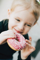 little beauty  blonde smiling girl eating pink donut. - 336032001