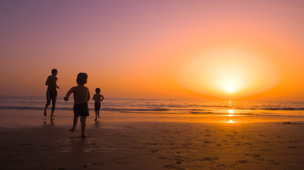 Father with kids playing in the beach at sunset