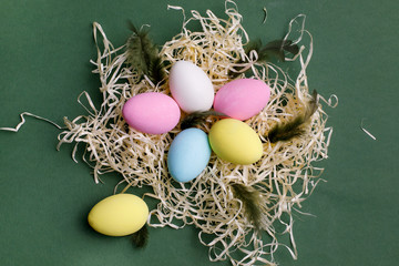 Easter basket with multi-colored eggs on a green background