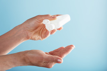 A bottle of Disinfectant gel in your hands on a blue background. Antiseptic treatment of hands from bacteria Sanitizer.