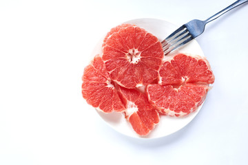 
sliced ​​red grapefruit on a white plate on a white background