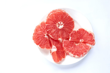 
sliced ​​red grapefruit on a white plate on a white background