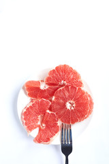
sliced ​​red grapefruit on a white plate on a white background