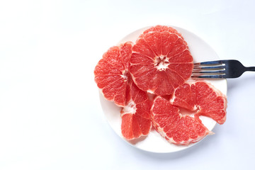 sliced ​​red grapefruit on a white plate on a white background
