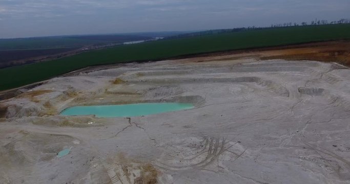 Aerial view of open pit kaolin clay mine (kaolinite quarry) with turquoise pool of water