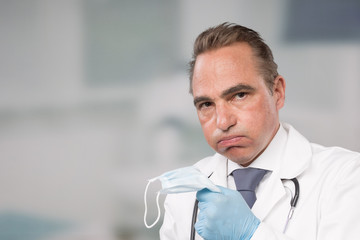 over strained doctor in lab coat and tie in front of a clinic room