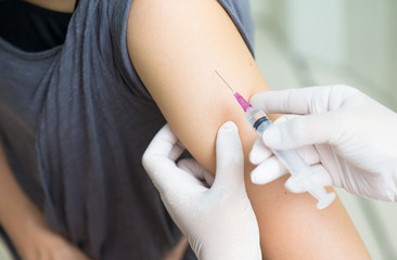 close up doctor's hand injecting for vaccination in the shoulder woman patient.Vaccine for protection HPV (Human Papillomavirus) infection.Vaccination for coronavirus treatment.