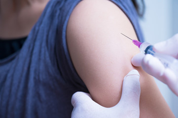 close up doctor's hand injecting for vaccination in the shoulder woman patient.Vaccine for protection HPV (Human Papillomavirus) infection.Vaccination for coronavirus treatment.