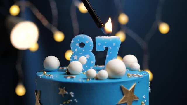 Birthday cake number 87 stars sky and moon concept, blue candle is fire by lighter and then blows out. Copy space on right side of screen if required. Close-up and slow motion