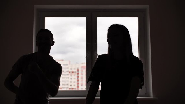 The silhouette of the newlyweds on the background of the windows dancing in their apartment.