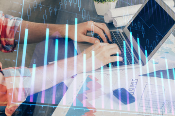 Double exposure of stock graph with businessman typing on computer in office on background. Concept of hard work.