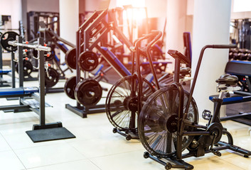 Fitness hall with sport bikes. Metal bicycle trainers, equipment in gym.