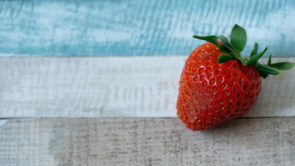 Close up of strawberry on colored wooden background