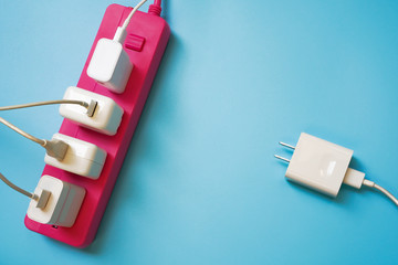 White mobile charger plugs full occupied on pink extension power strip and one plug left await in...