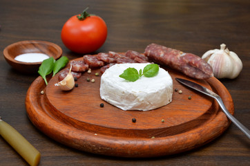 Camembert cheese and sausage food on a wooden board