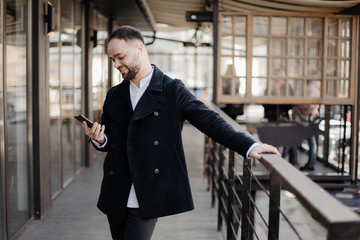 Portrait of fashionable well dressed man with beard posing outdoors