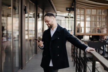 Portrait of fashionable well dressed man with beard posing outdoors