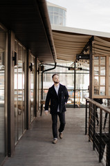 Portrait of fashionable well dressed man with beard posing outdoors