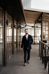 Portrait of fashionable well dressed man with beard posing outdoors