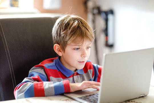 Little school kid making school homework on computer. Child learning on pc. Hard-working boy making exercise during quarantine time from corona pandemic disease. Homeschooling concept.