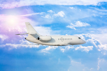 White luxury private airplane flies in the air above the clouds