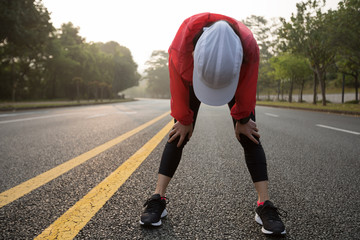 Young woman runner taking a rest during running on city road