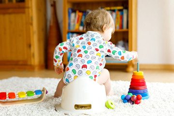 Closeup of cute little 12 months old toddler baby girl child sitting on potty.