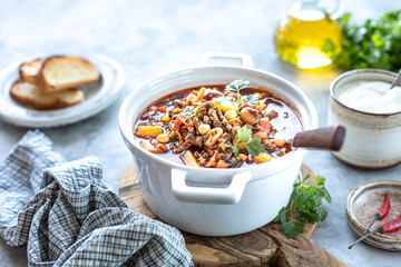 Thick minced meat soup with tomatoes, beans, chickpeas and vegetables. Healthy dinner. View from above. top view