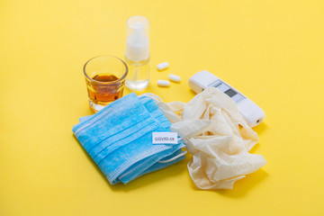 medical mask, gloves and disinfectant on yellow background
