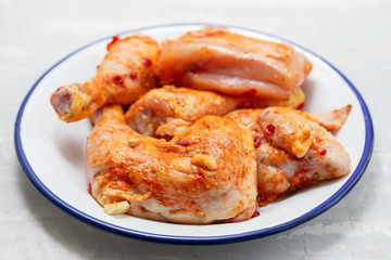 raw chicken with sauce on white dish on yellow background