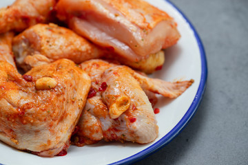 raw chicken with sauce on white dish on yellow background