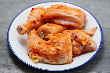 raw chicken with sauce on white dish on yellow background