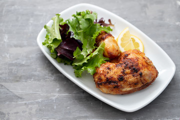 grilled chicken with lemon and salad on white dish