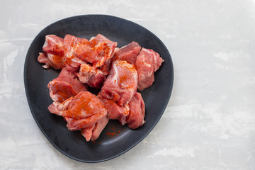 marinated meat on black dish on ceramic background
