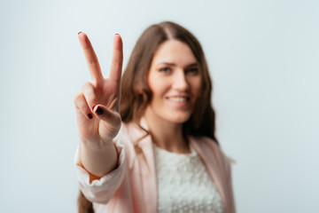 long-haired beautiful brunette girl showing two fingers, positive or peace gesture, on white