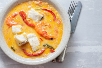 fish with shrimps and pepper in sauce in the dish on ceramic background