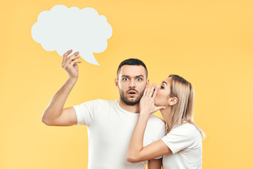 Young woman whispering secrets to man with paper thought bubble