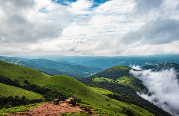 Naklejka premium Cloud layers on mountain horizon with green grass