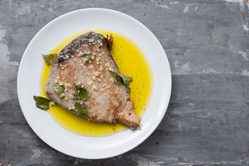 fried tuna with garlic, bay leaf and olive oil on white plate