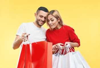 Young happy couple holding shopping bags in hands and looking their purchase