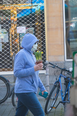 A woman wearing a mouth protection carries a spring flower in Frankfurt Bockenheim during the Corona Virus Crisis.
