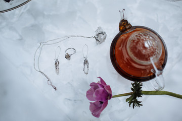 Fototapeta na wymiar The bride's earrings and ring in the form of frozen minerals next to a Chinese teapot