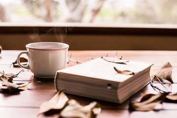 white book and coffee cup with leafs around