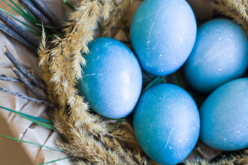 Easter holiday decorations, background. Basket with painted blue eggs, with bars, branches, flowers. Religion.