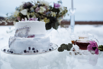 Glass table with a wedding bouquet, on which there is a wedding cake